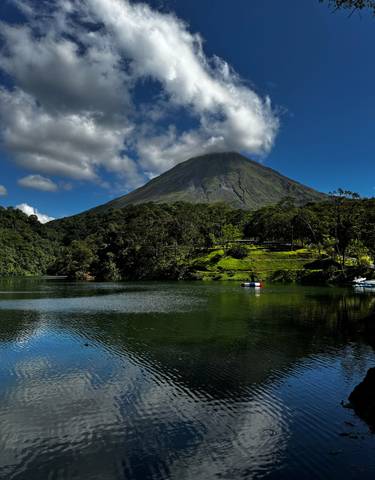 Arenal Volcano with lush greenery and a lake in the foreground.