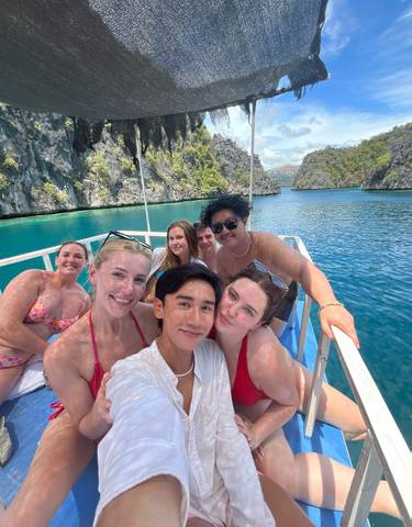 Group of people posing on a boat in tropical waters.