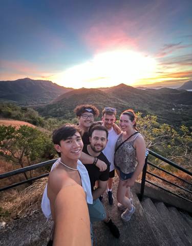 Group of people posing at a scenic viewpoint during sunset.