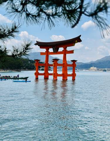 Red Torii gate in the water with mountains in the background.