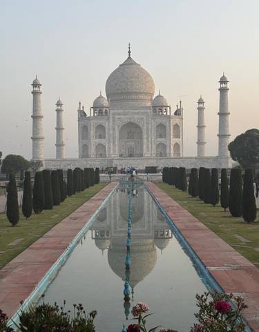 The Taj Mahal with visitors and reflections in the pool.
