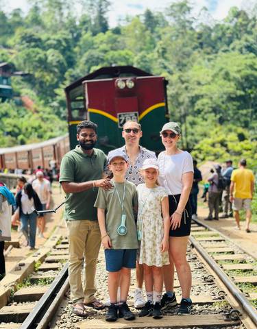 Family posing in front of a colorful train.