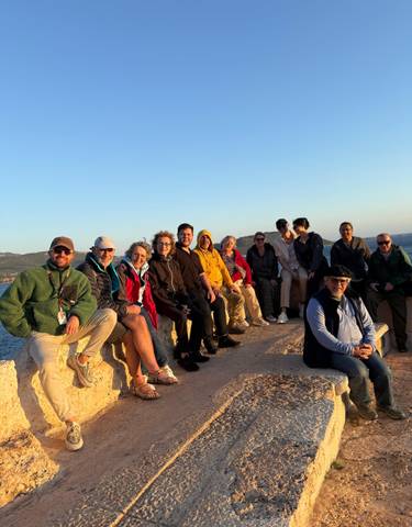 Group of people sitting at a scenic viewpoint.