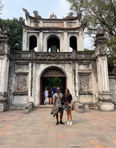 Couple posing in front of a historic gate with ornate carvings.