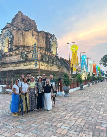 Group of tourists posing in front of an ancient temple with flags.
