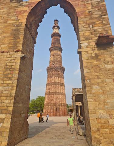 View of Qutub Minar through stone archways.