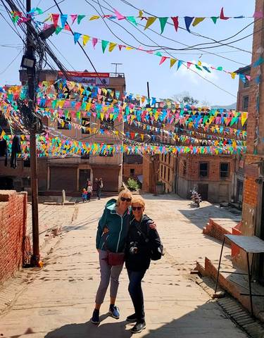 Two people posing on a street festooned with colorful flags.