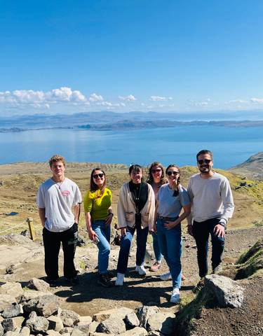 Group of people smiling with scenic cliffs and sea in the background.