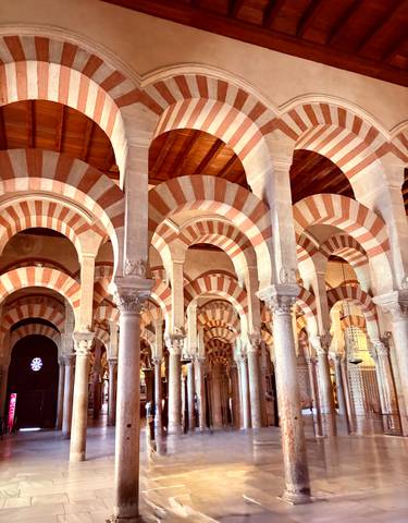 Arched interior of a historic mosque with striped patterns.