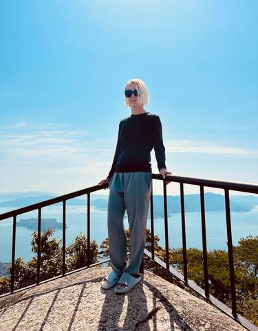 Person standing by a railing overlooking a scenic bay.