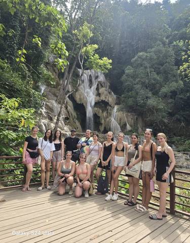 Group in front of a waterfall surrounded by trees.