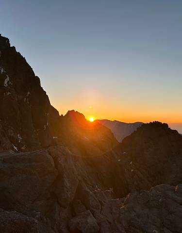 Sun setting behind a mountain ridge.