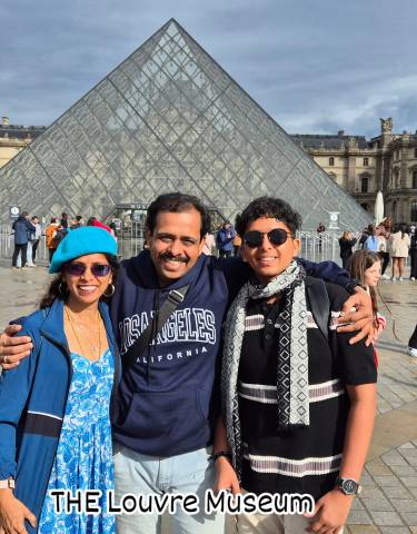 Family poses in front of a glass pyramid at a famous museum.