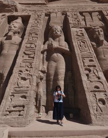 Tourist standing in front of massive Egyptian statues.