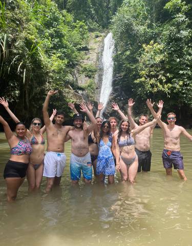 A group of people posing in front of a waterfall.