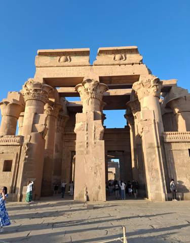 An ancient temple with carved columns under a clear sky.
