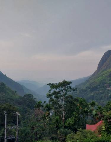 Scenic view of lush mountains and cloudy sky.
