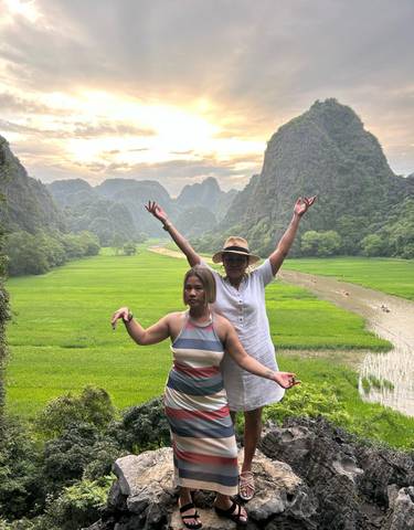 Two women posing in front of a scenic landscape with karst mountains.