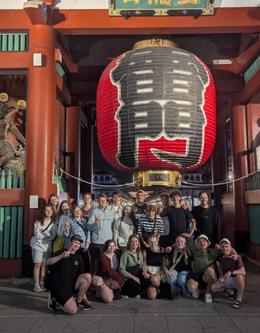 A group standing under a large red lantern at night.