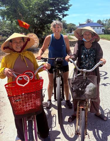 Three local women with baskets posing with a tourist in the middle.