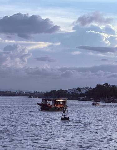 Boats on a river at dusk with a cloudy sky.