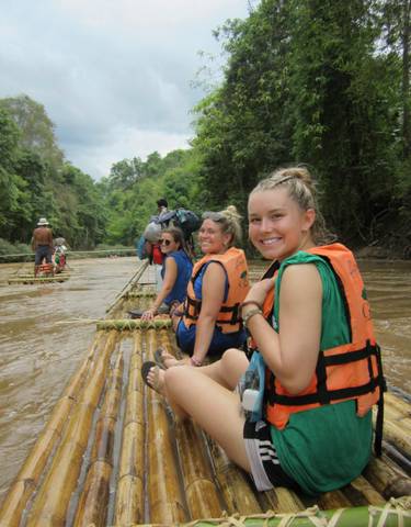 People rafting on a bamboo raft along a river.