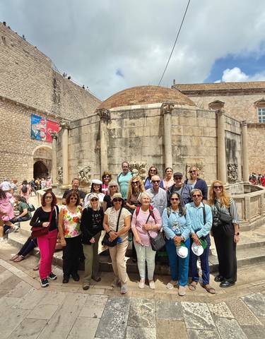 Group of people posing in front of an ancient stone fountain.