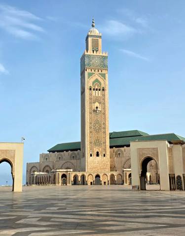 Tall mosque with intricate tile work under a clear sky.