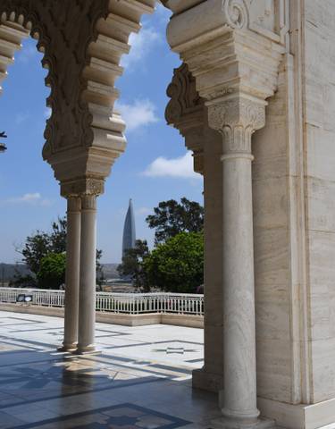 Modern skyscraper seen between traditional architectural columns.