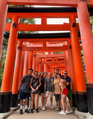 Group posing at the iconic red torii gates of Fushimi Inari Shrine.