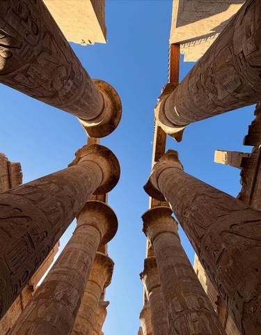Ancient Egyptian columns with carvings under a clear blue sky.