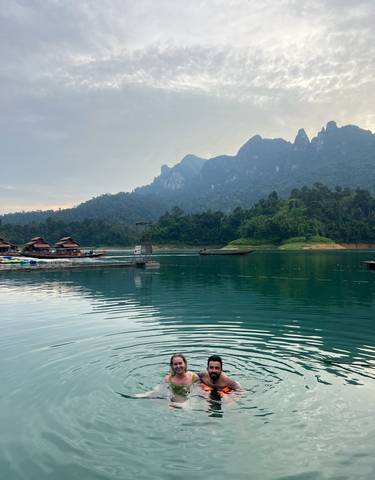 Lake with houses on stilts and forested mountains.