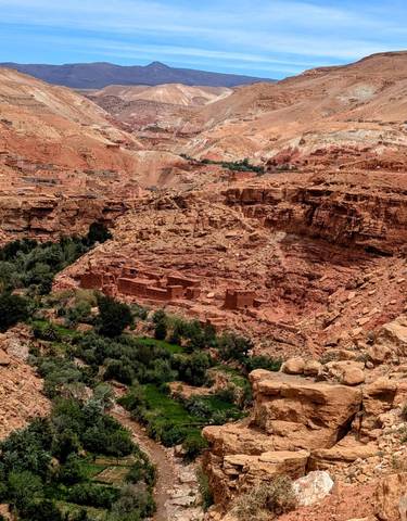 Ancient village with red rocks and green vegetation.