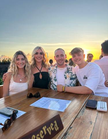 Group of people smiling at a table during sunset.