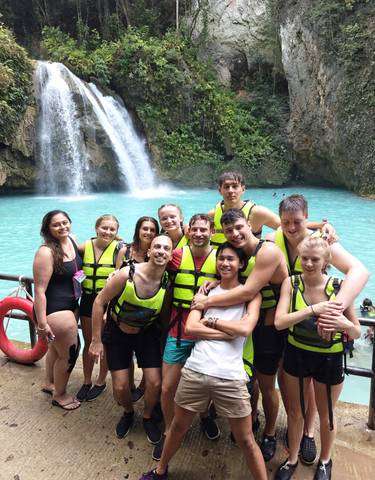 Group with life jackets in front of a tall waterfall.