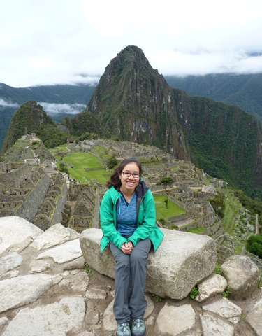 Woman smiling in front of the ancient ruins of Machu Picchu.