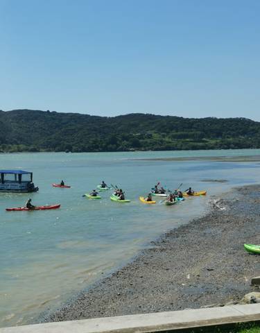 People kayaking on a blue lagoon with hills in the background.