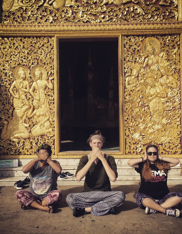 Three people posing with a golden temple backdrop.