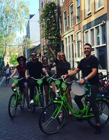 Group of people smiling and riding bicycles in a city street.