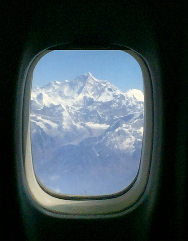 View of snow-capped mountains through an airplane window.