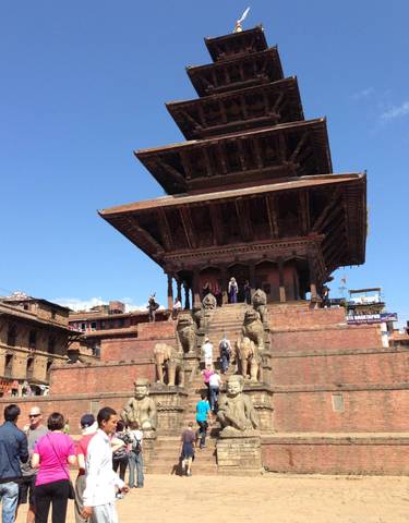 Pagoda style temple with people and statues at the entrance.