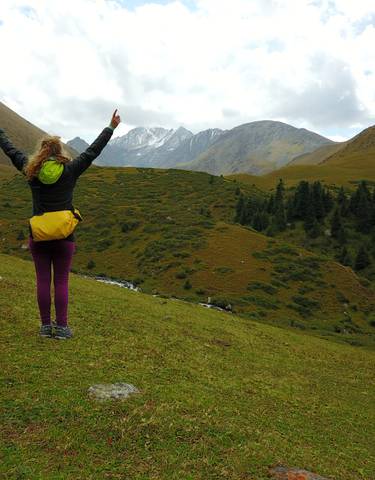 Hiker with arms raised in a mountainous landscape.