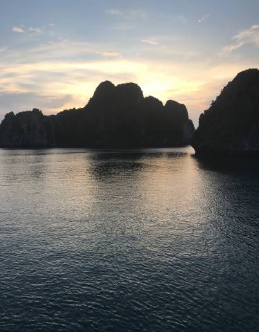 Scenic view of a bay with limestone karsts at sunset.