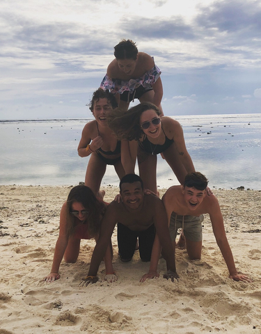 Group of friends playing on a sandy beach.