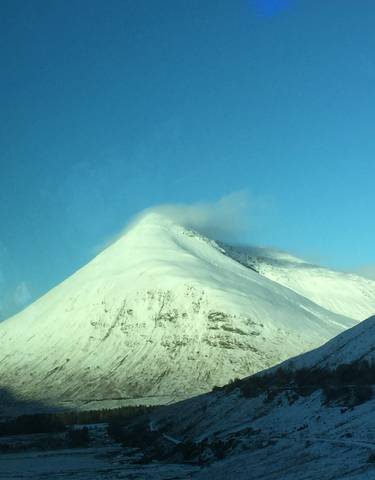 Snow-covered mountain peak with clear blue sky.