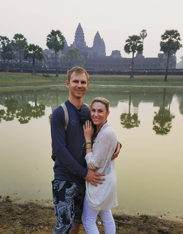 Couple embracing in front of a temple with water reflection.