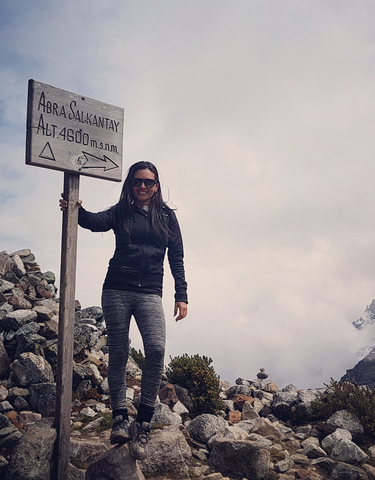 Smiling woman posing next to a sign at high altitude in the mountains.