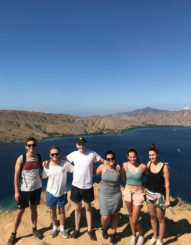 Group enjoying a scenic view from a hill overlooking the sea.
