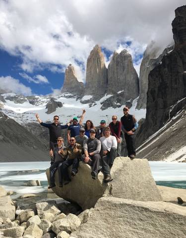 Group of hikers posing in front of snow-covered mountains.