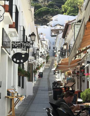 Charming narrow street lined with white buildings and shops.